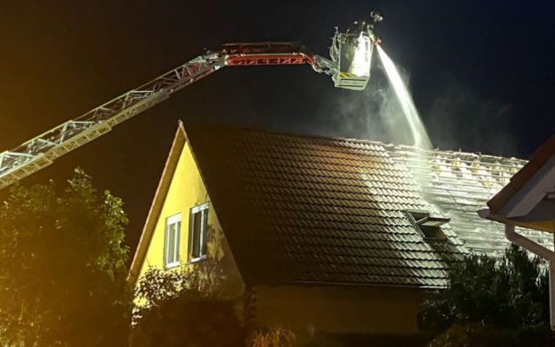 Ein Feuerwehrmann im Kran versucht das Feuer über das Dach zu löschen.